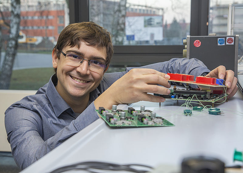 Dr. Jacob Maxa zeigt ein entwickeltes Testsystem für die wärmespeichernde Beschichtung im Labormaßstab sowie aus einer industriellen Anwendung. (Foto. Universität Rostock/ Julia Tetzke).