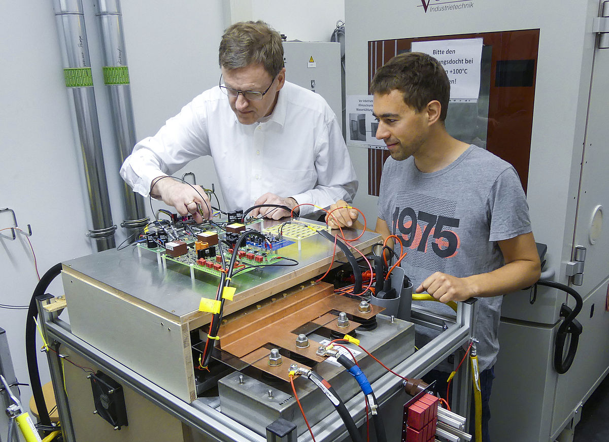 (v.l.) Professor Hans-Günter Eckel prüft einen Versuchsaufbau von Dr. Jan Fuhrmann zum Testen von Leistungshalbleitern (Copyright: Universität Rostock / Steffen Sänger).